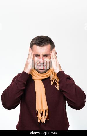 Ein Mann hält seine Hand wegen Kopfschmerzen auf dem Kopf, ein Porträt eines Mannes auf weißem Hintergrund, der Hals eines Mannes ist in einen Schal gewickelt. Stockfoto