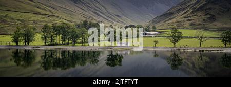 Ein Panoramablick auf Bäume und Grünflächen auf der anderen Seite des Buttermere Lake in England Stockfoto