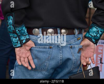 Ein Mann trägt einen Gürtel, der mit Silberdollar verziert ist, auf dem indischen Markt von Santa Fe in Santa Fe, New Mexico. Stockfoto