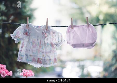 Niedliche Baby-Mädchen Kleidung hängt auf der Wäscheleine. Stockfoto