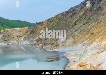 Heißer mineralisierter See mit Thermalquelle und rauchenden Fumarolen in der Caldera des Vulkans Golovnin auf der Insel Kunashir Stockfoto