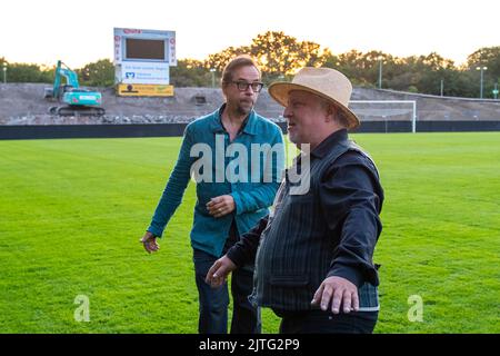 30. August 2022, Nordrhein-Westfalen, Münster: Tatort-Schauspieler Jan Josef Liefers (l.) und Axel Prahl stehen auf dem Stadionrasen zusammen. Seit 20 Jahren sind Kommissar Frank Thiel (Axel Prahl) und Kriminalwissenschaftler Prof. Karl-Friedrich Boerne (Jan Josef Liefers) im WDR Tatort Münster im Einsatz. Foto: David Inderlied/dpa Stockfoto