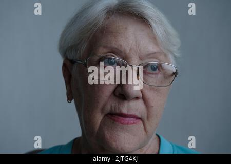 Nahaufnahme des Porträts einer älteren Frau mit grauen Augen in der Brille Stockfoto