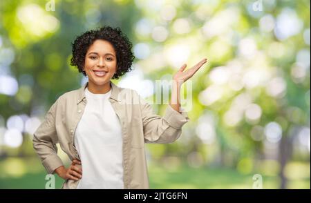 Glückliche Frau, die etwas mit ihrer Hand zeigt Stockfoto