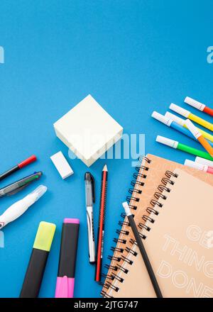 Bleistifte, Radierer, Stifte, Haftnotizen, Marker, Notebook und andere Büromaterialien auf dem blauen Tisch. Zurück zum Schulkonzept. Draufsicht mit Kopierbereich. Stockfoto