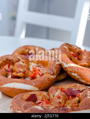 Traditionelle bayerische Brezeln gefüllt mit Käse, Trockenwurst und Paprika auf einem weißen Tisch. Stockfoto