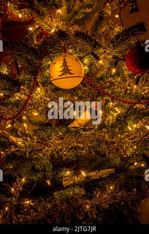 Goldene und rote Weihnachtsbaumschmuck mit Lichtern und Kugeln Stockfoto