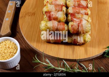Cassava-Spieße in Speck eingewickelt, Cassava-Medaillon. Stockfoto