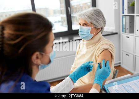 Krankenschwester mit Spritze, die der Frau Injektion macht Stockfoto