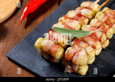 Cassava-Spieße in Speck eingewickelt, Cassava-Medaillon. Stockfoto