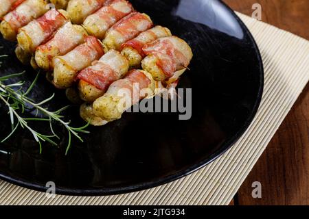 Cassava-Spieße in Speck eingewickelt, Cassava-Medaillon. Stockfoto