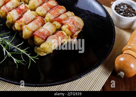 Cassava-Spieße in Speck eingewickelt, Cassava-Medaillon. Stockfoto