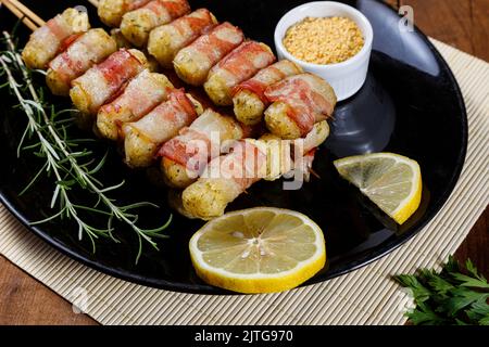 Cassava-Spieße in Speck eingewickelt, Cassava-Medaillon. Stockfoto