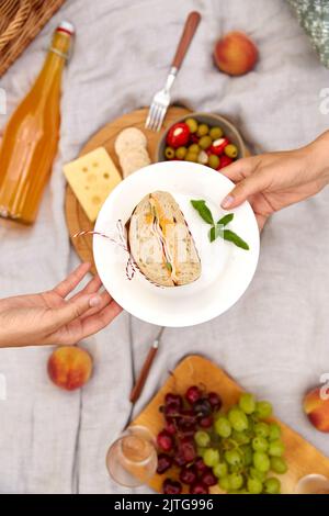 Nahaufnahme der Hände, die das Sandwich beim Picknick halten Stockfoto