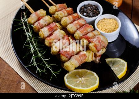 Cassava-Spieße in Speck eingewickelt, Cassava-Medaillon. Stockfoto