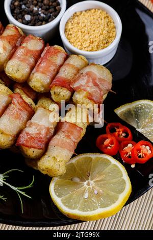 Cassava-Spieße in Speck eingewickelt, Cassava-Medaillon. Stockfoto