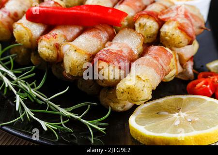 Cassava-Spieße in Speck eingewickelt, Cassava-Medaillon. Stockfoto