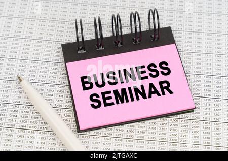 Geschäftskonzept. Auf Berichtsdokumenten und Diagrammen gibt es einen Stift und einen Notizblock mit der Aufschrift - BUSINESS SEMINAR Stockfoto