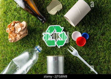 Grünes Recycling-Schild mit Hausmüll auf Gras Stockfoto