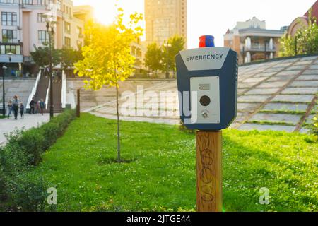 Panikalarm, Polizei, Notausschalter im öffentlichen Park. Blaue Box mit Videokamera und rot blauem Warnlicht oben Stockfoto