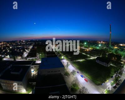 Nächtliche Panoramasicht auf die alte europäische Industriestadt bei Vollmond, lange ausstrahlende Straßen, Nymburk City Stockfoto