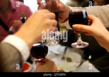 Unschärfe-Effekte bei Toasten Brillen im Hintergrund. Klirrende Gläser mit Alkohol und Toasten, Party. Gesellschaft von Freunden. Feiertagskonzept wird gefeiert. Gemeinsam. Aus Stockfoto