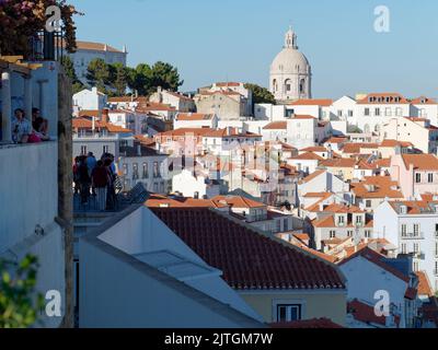 Aussichtspunkt Miradouro de Santa Luzia in Lissabon Portugal über die Dächer der Stadt, während Touristen die Aussicht an einem Sommerabend genießen. Stockfoto