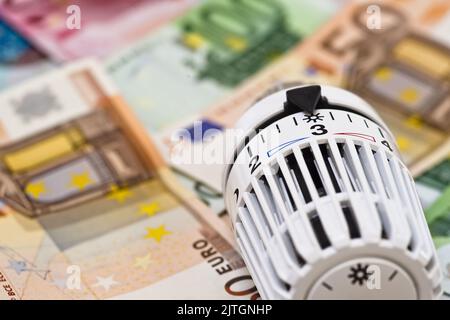 Heizthermostat und Banknoten, steigende Heizkosten Stockfoto