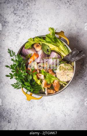 Gemüse und Kräuterzutaten für Suppe im holländischen Ofen mit hellem Hintergrund Stockfoto