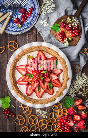 Flache Lay of Strawberry Cream Pie in Keramikschale mit frischen Beeren und Brezeln Stockfoto