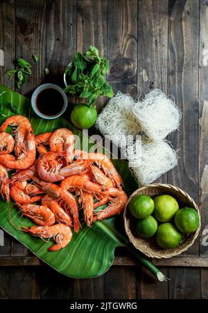 Zutaten für die thailändische Küche - Garnelen, Reisnudeln, Minze, grüne Zwiebel, Palmblatt Zusammensetzung, Draufsicht Stockfoto