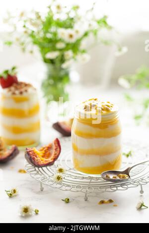 Schichten von Joghurt und Passionsfrucht Quark in kleinen Glasgefäßen. Jedes Dessert wird mit Passionsfrucht-Samen gekrönt. Stockfoto