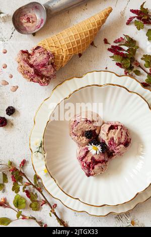 BlackBerry-Ripple- und Schokoladeneis in einer Schüssel und in einem Waffelkegel serviert. Stockfoto