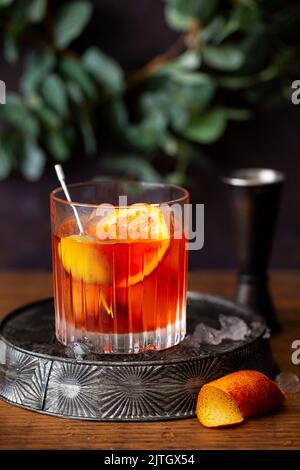 Negroni mit italienischen Orange Bitters und garniert mit Oliven und einer Scheibe Orange. Stockfoto