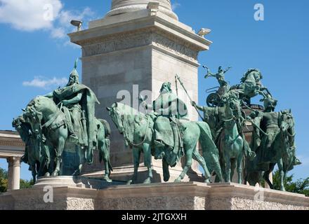 Denkmäler auf dem Heldenplatz in der Nähe des Parlamentshauses in Budapest zeigen große Säulen und Statuen mit blauem Himmel darüber. Helden auf dem Pferderücken werden dargestellt. Stockfoto