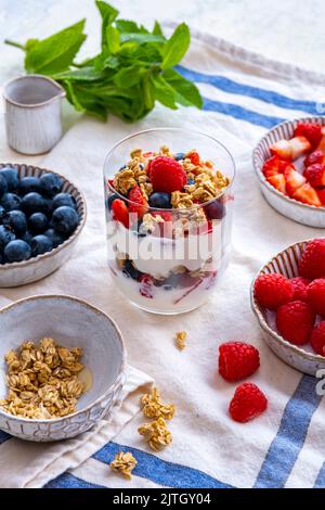 Joghurt Frühstück Parfait im Glas, Heidelbeeren, Erdbeeren, Himbeeren und Müsli auf der Seite. Stockfoto