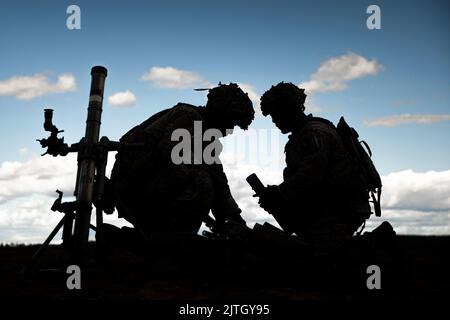 Rovaniemi Training Area, Finnland. 11. August 2022. SPC der US-Armee. Brandon Almaguer, links, und U.S. Army SPC. Mattox Harrell, beide Infanteristen mit indirektem Feuer, die der Viper Company, 1. Bataillon, 26. Infanterie-Regiment, 2. Brigade Combat Team, 101. Airborne Division (Air Assault), zugewiesen wurden, reorganisiert nach Abschluss einer Feuermission zur Unterstützung des Manövers des Unternehmens während einer multinationalen Live-Fire-Übung im Trainingsgebiet Rovaniemi, Finnland, 11. August 2022. Die LFX war Teil der finnischen Sommerübung, bei der US- und finnische Truppen die Möglichkeit hatten, miteinander zu trainieren Stockfoto