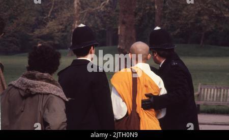 30. April 1980, London, Großbritannien: Britische Polizei begleitet einen buddhistischen Mönch während der sechstägigen Belagerung der iranischen Botschaft aus dem Gebiet. In London. Vom 30. April bis zum 5. Mai 1980 übernahm eine Gruppe von sechs bewaffneten iranischen Dissidenten, die sich gegen Ayatollah Khomeini, den religiösen Führer, der 1979 an die Macht kam, ausssetzten, die iranische Botschaft am Prince's Gate in South Kensington, London. Die iranische Gruppe nahm 21 Geiseln, von denen zwei getötet wurden. In der Nähe der Belagerungsszene machten Anhänger von Khomeini ihre Ansichten mit einem Protest bekannt. Die dramatische sechstägige Belagerungszeit endete, als britische SAS-Elitetruppen aus der Welt der Elite gingen Stockfoto