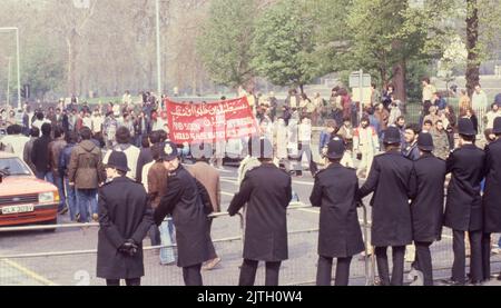 30. April 1980, London, Vereinigtes Königreich: Polizei unter Kontrolle der iranischen Unterstützer mit einem Banner der protestmarsch in London während der sechstägigen Belagerungsaktion der iranischen Botschaft. Vom 30. April bis zum 5. Mai 1980 übernahm eine Gruppe von sechs bewaffneten iranischen Dissidenten, die sich gegen Ayatollah Khomeini, den religiösen Führer, der 1979 an die Macht kam, ausssetzten, die iranische Botschaft am Prince's Gate in South Kensington, London. Die iranische Gruppe nahm 21 Geiseln, von denen zwei getötet wurden. In der Nähe der Belagerungsszene machten Anhänger von Khomeini ihre Ansichten mit einem Protest bekannt. Die dramatische sechstägige Belagerungszeit endete Stockfoto