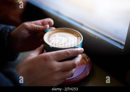 Kaffee bietet den besten Komfort. Nahaufnahme einer Frau, die in einem Café einen Cappuccino genießt. Stockfoto