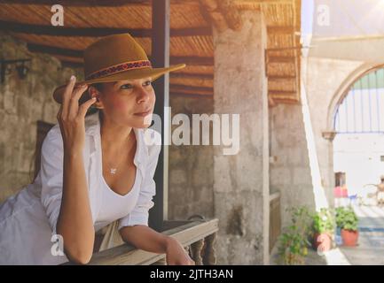 Frau mit Cowboyhut auf der Veranda sitzend, Jalisco Mexiko, Porträt einer glücklichen Frau mit Hut. Selektiver Fokus. Stockfoto