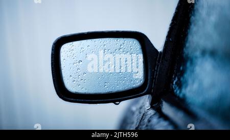 Das Konzept der eingeschränkten Sicht auf Straßen. Auto Rückspiegel. Auf dem Hintergrund von Nebel, in Tropfen von Tau. Stockfoto