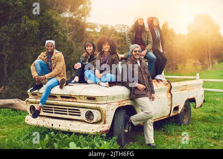 Kaltes Wetter, warme Herzen. Porträt einer Gruppe von Freunden, die auf einem Feld um einen alten Lastwagen posierten. Stockfoto