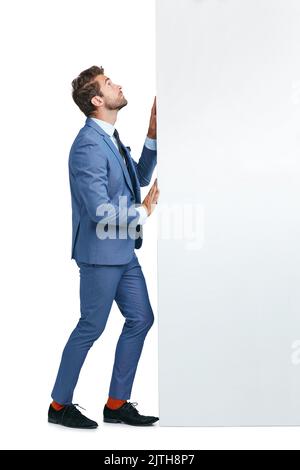Erfolg beginnt mit der Entscheidung, es auszuprobieren. Studioaufnahme eines hübschen Geschäftsmannes, der eine Wand auf einen weißen Hintergrund schiebt. Stockfoto