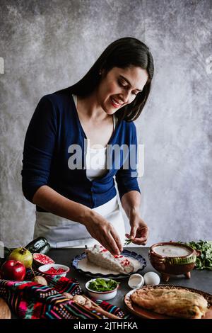 mexikanische Frau Kochen Chiles en nogada Rezept mit Poblano Chili und Zutaten, traditionelles Gericht in Mexiko Stockfoto