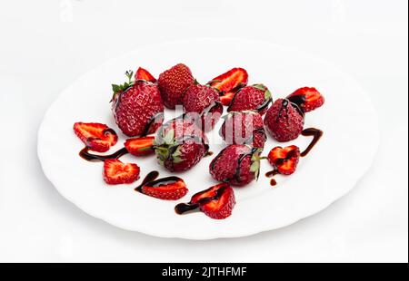 Nahaufnahme, Draufsicht Erdbeere mit Schokoladensauce auf weißem Teller, Studiofoto. Gesundes Lebensmittelkonzept, Bio-Lebensmittelkonzept, einfaches und glückliches Lebensgefühl Stockfoto