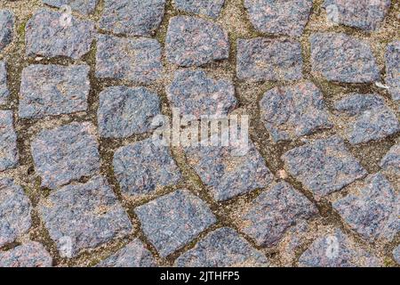 Detail Granit Gehweg, Textur oder Hintergrund, Herbst. Steinstraße oder Gehweg aus Granit. Alte Straße Kopfsteinpflaster als Hintergrund. Abstrakte Vintage-Pavemen Stockfoto