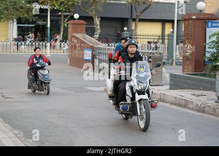 In Kunming fahren Menschen mit Elektrorollern und chinesische SWAT-Polizisten mit einem Motorrad Stockfoto