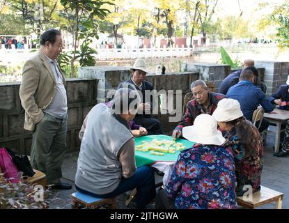 Ältere Chinesen spielen Mahjong Brettspiel auf einem Tisch in einem öffentlichen Park in Kunming . Stockfoto