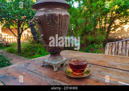 Teetrinken aus einem Vintage-Samowar im Garten Stockfoto